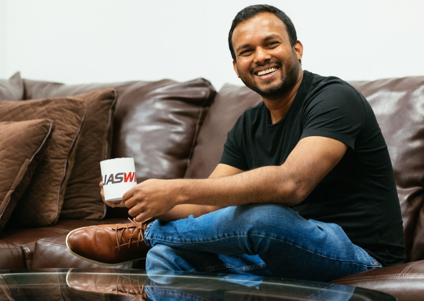 Man with coffee mug smiling sitting on a couch